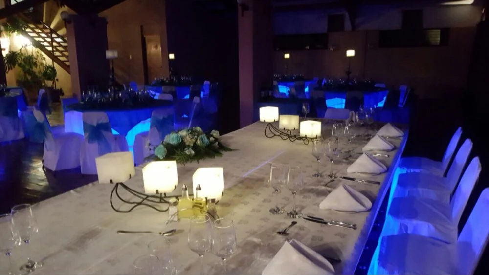 Customer event setup with several blue illuminated tables and a decorated head table