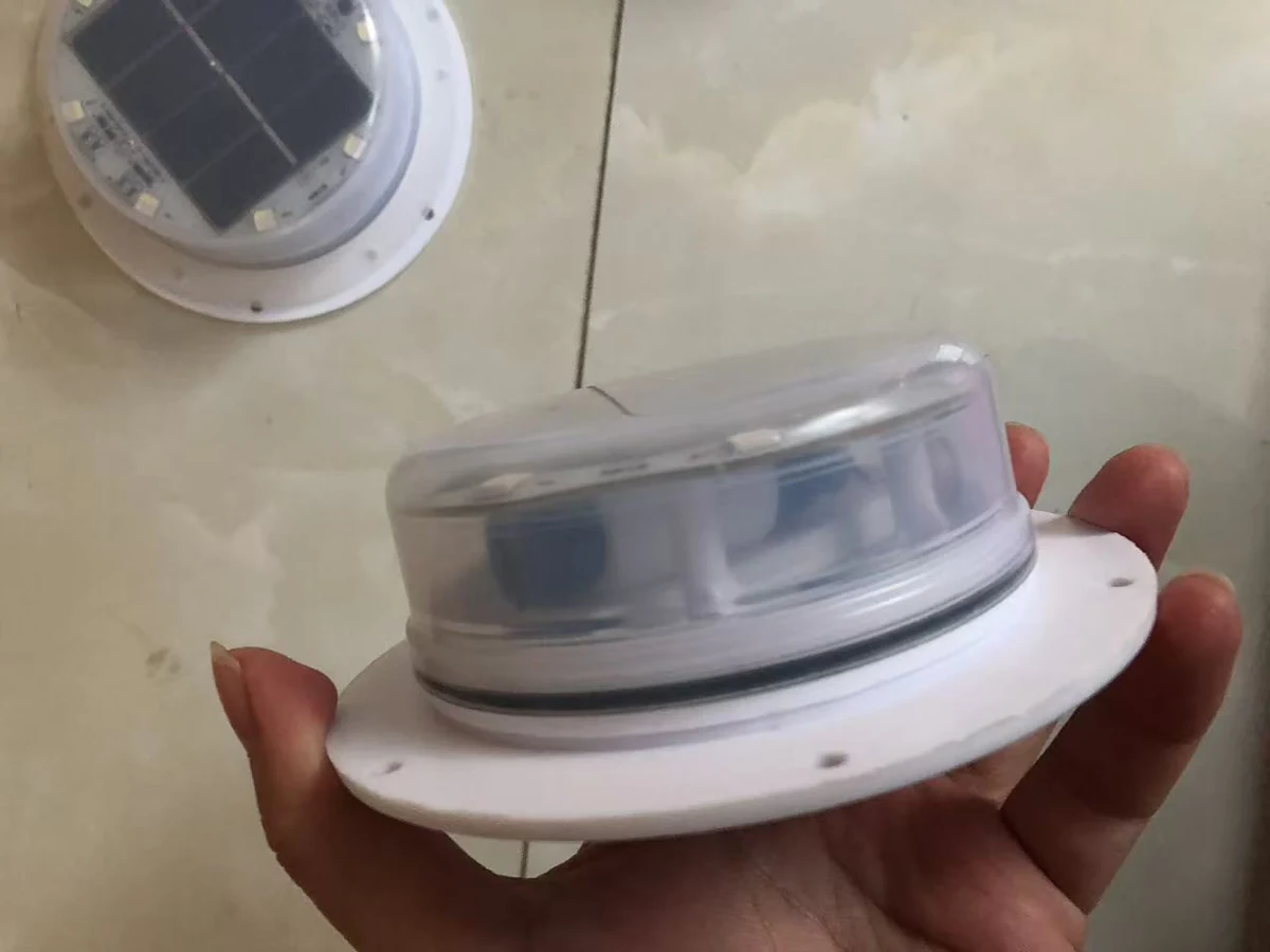 Solar LED module held in a hand, showing the transparent cover, panel and mounting flange