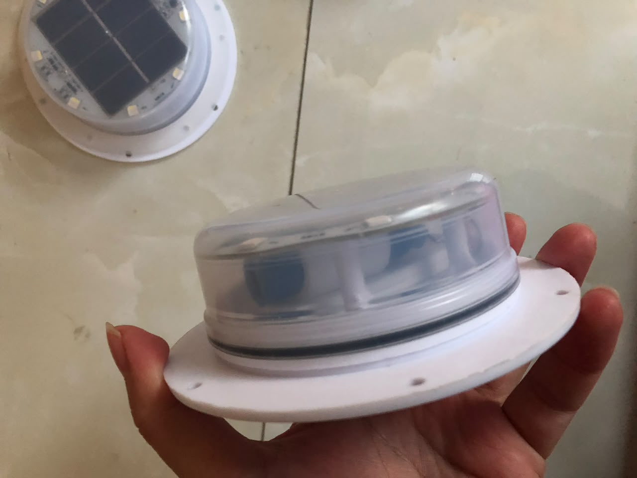 Solar LED module held from the side with its mounting flange and sealing ring visible