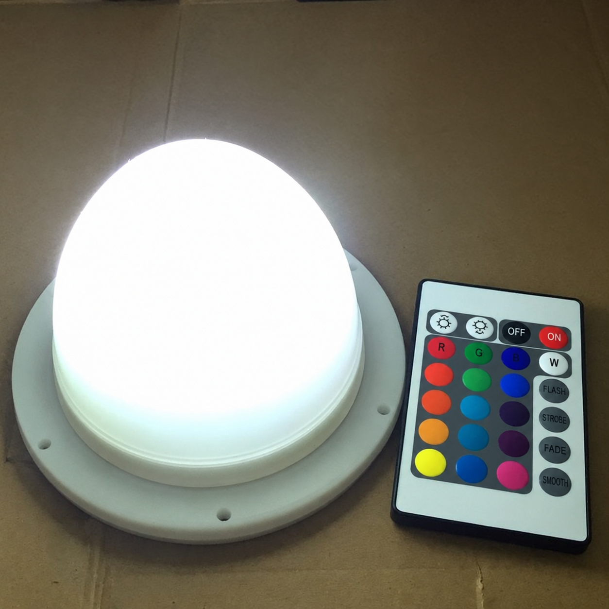 Archived VC-L120 replacement light illuminated white beside a multi-colour remote control