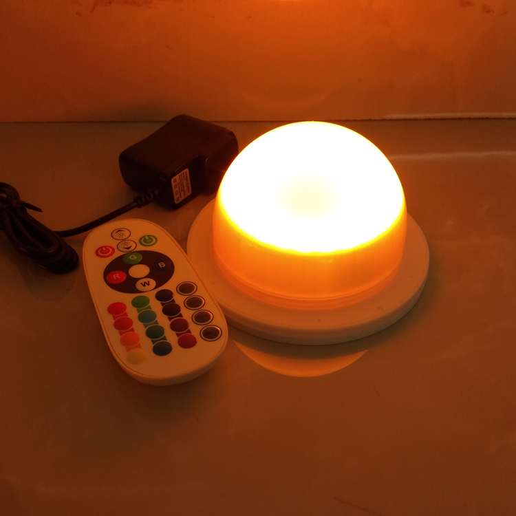 Real Vcan dome LED module showing an orange-toned lighting effect beside a remote