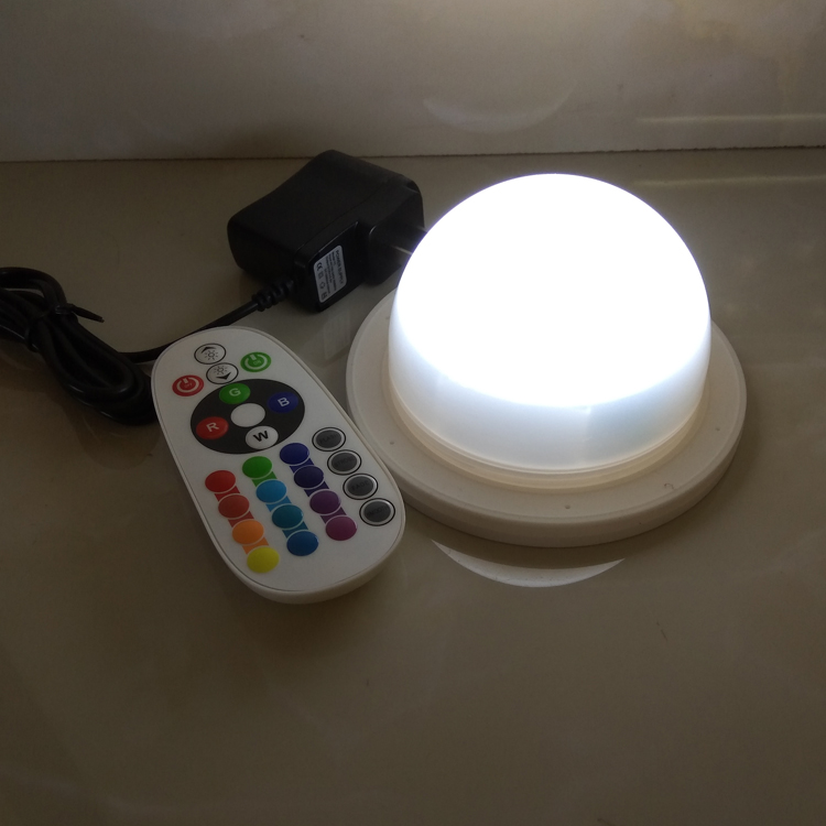 Real Vcan dome LED module emitting white light beside a remote and power adapter